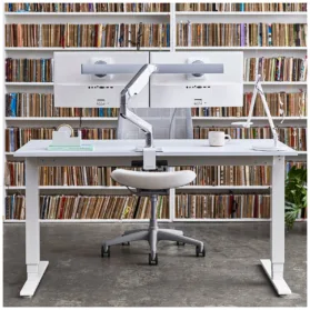 A Humanscale Float sit-to-stand table with a black frame and a white top. The table is adjustable in height, so you can switch from sitting to standing throughout the day.